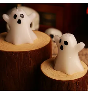 Set of two white ghost shaped candles on rustic wooden stumps for Halloween decor.