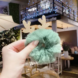 Vue détaillée d'un chouchou en peluche verte avec des bois de renne dorés scintillants.