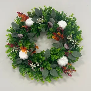 Detailed view of autumn eucalyptus wreath with white pumpkins and colorful flowers