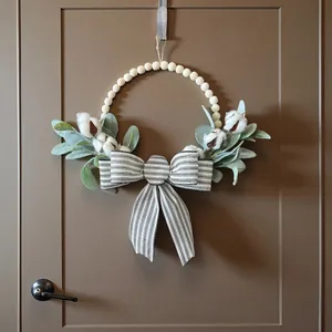 Couronne minimaliste avec nœud rayé, perles en bois et coton sur une porte brune.