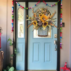 Autumn sunflower and pinecone harvest wreath in galvanized metal bucket on blue door.