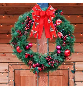Large red double-layer Christmas bow with festive white tree patterns on a green wreath