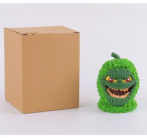 Adorno de Halloween de monstruo calabaza verde musgoso junto a caja de cartón marrón
