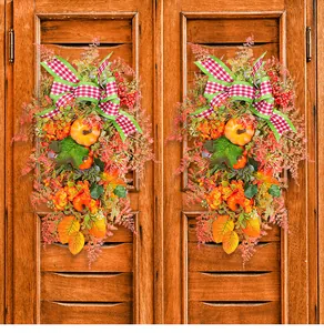 Detail der Herbst-Erntedankkranz mit Kürbis und rot karierter Schleife an Holztür