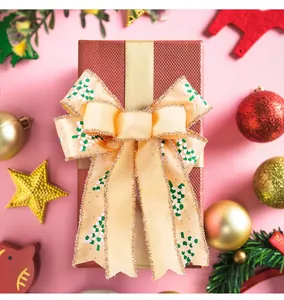 Close-up of champagne double-layer Christmas bow with glitter edges on a gift box.