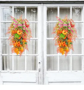 Ein Paar Ernte-Herbstkränze mit Kürbissen und karierten Bändern am weißen Fenster