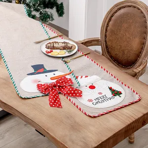 Festive linen Christmas table runner with Santa and Snowman motifs on a wooden table