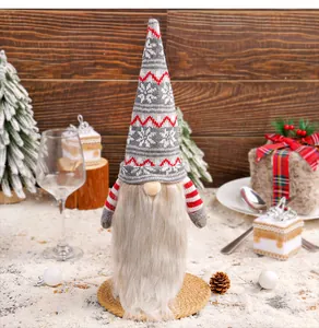 Macro detail of a knitted Christmas gnome bottle cover featuring white snowflake patterns