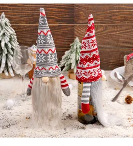 Two festive knitted Christmas gnome wine bottle covers with snowy holiday table decor