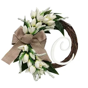 Decoratieve deurkrans met witte tulpen, strik van jute en een grote witte letter C.