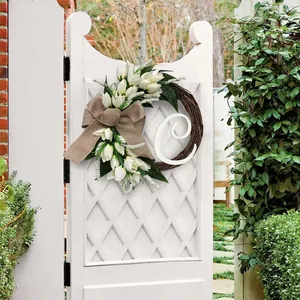 Elegante kunstmatige witte tulpenkrans met jute strik en witte letter C op de poort