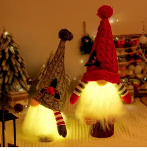 Close-up view of glowing Christmas gnome ornaments with warm LED lights and knitted hats.