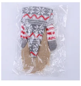 Detail view of a knitted Christmas gnome wine bottle cover in plastic packaging