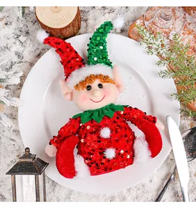 Christmas elf doll with sequined hat on a white dinner plate for table decoration