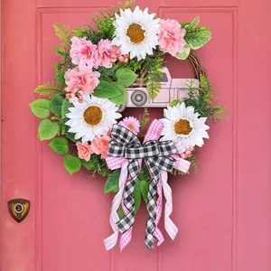 Elegante ghirlanda floreale rosa con girasoli e camioncino su una porta di legno rosa.
