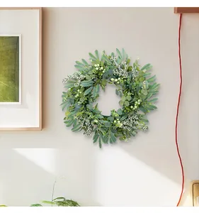 Artificial eucalyptus and berry wreath hanging on a neutral beige interior wall.