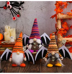 Tre gnomi di peluche di Halloween con ali di pipistrello su un tavolo rustico in legno