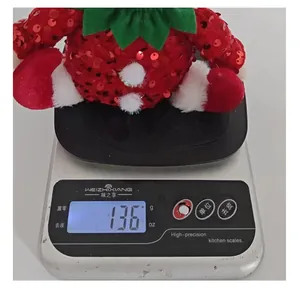 Detail of a sequined Christmas elf doll being weighed at 136 grams on a scale.