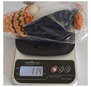 Dettaglio del peso che mostra 114g su una bilancia per lo gnomo di peluche Halloween.
