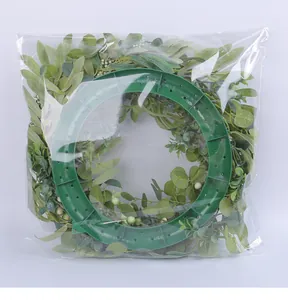 Detailed back view of artificial eucalyptus and berry wreath in transparent plastic packaging