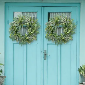 Artificial eucalyptus berry wreath hanging on a blue front door for holiday decor
