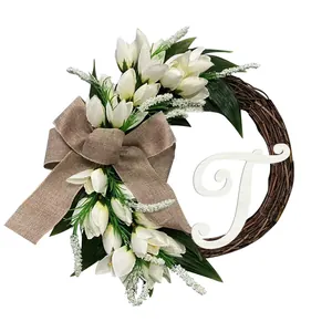 Detail van witte kunsttulpen krans met jute strik en monogram letter T decoratie