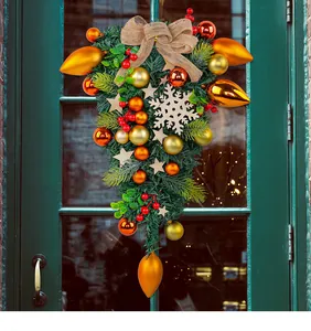 Elegant Christmas teardrop wreath with gold ornaments and burlap bow on a green door