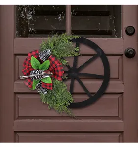 Vue détaillée d'une couronne de roue de chariot de Noël avec pommes de pin et nœud à carreaux.