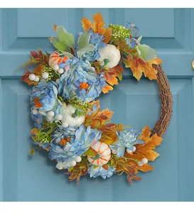 Detailansicht eines Herbstkranzes mit blauen Pfingstrosen und Kürbissen an blauer Tür