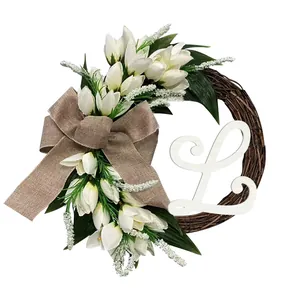 Detail van een wijnstok krans met witte tulpen, een jute strik en houten letter L