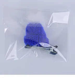 Vista detallada de una pinza para el pelo con forma de mini gorro de punto azul y pompón