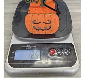 Detailansicht einer Halloween-Kürbis-Laterne, die auf einer Digitalwaage 25g anzeigt