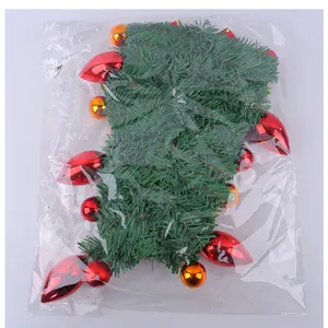 Detailed view of artificial Christmas garland with ornaments in clear plastic packaging.