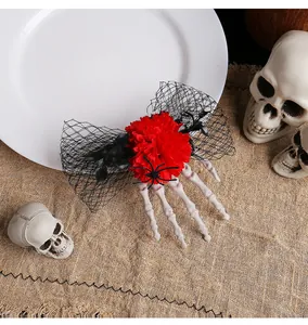 Vue détaillée d'une pince à cheveux main de squelette avec rose rouge et maille noire