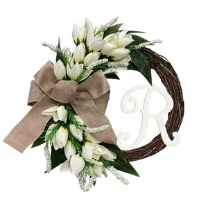 Gedetailleerde weergave van kunstmatige tulpenkrans met jute strik en witte letter R decoratie