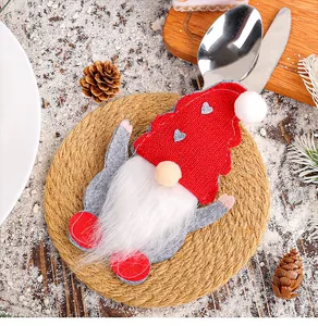 Close-up of a festive red and grey Christmas gnome felt cutlery holder on a woven mat.