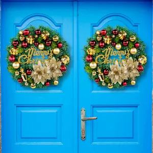 Par de coronas navideñas con adornos rojos y dorados sobre una puerta azul.