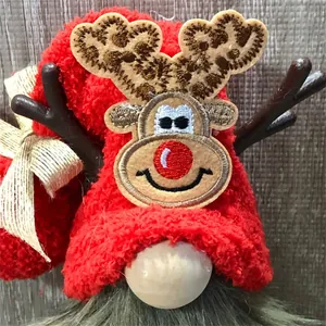 Detailopname van een kerstkabouterpop met rendiergewei en een rode pluchen kerstmuts.