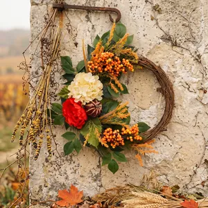 Decorative autumn harvest wreath with pumpkin, hydrangea, and berries on rustic stone wall