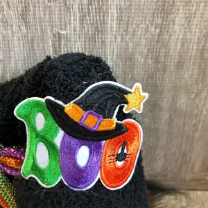Gedetailleerde close-up van het kleurrijke 'BOO' geborduurde embleem op een pluche pop.