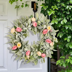 Detailed view of a spring floral wreath with pink roses and lamb's ear leaves on a white door