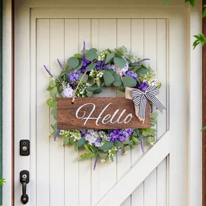 Ghirlanda di eucalipto artificiale con fiori viola e una scritta Hello sulla porta