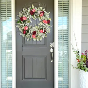 Floral wreath with lamb's ear leaves and pink roses hanging on a dark entrance door