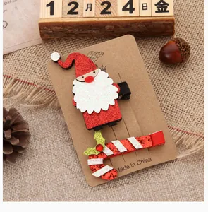 Detailed view of Santa Claus and candy cane glitter Christmas hair clips on a kraft paper card.