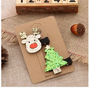 Detail of cute Christmas hair clips featuring a glittery reindeer and green tree on card.