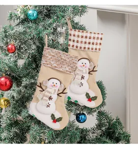 Detail of festive snowman Christmas stockings with plaid and striped cuffs hanging on tree