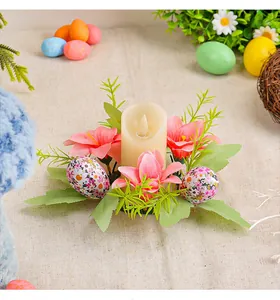 Detail of Easter egg candle holder with pink lilies and green leaves on beige fabric.