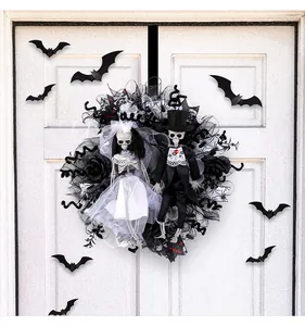 Vista detallada de una corona de Halloween con novios esqueletos en una puerta blanca.