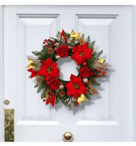 Ghirlanda di Natale con stelle di Natale rosse e rose appesa a una porta bianca