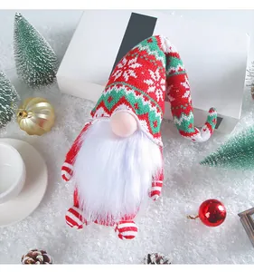 Close-up detail of a Christmas knitted gnome doll with a tall red hat on artificial snow.